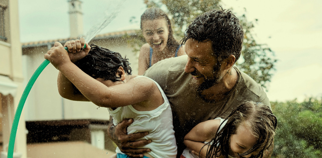A family playing with a garden hose in the backyard